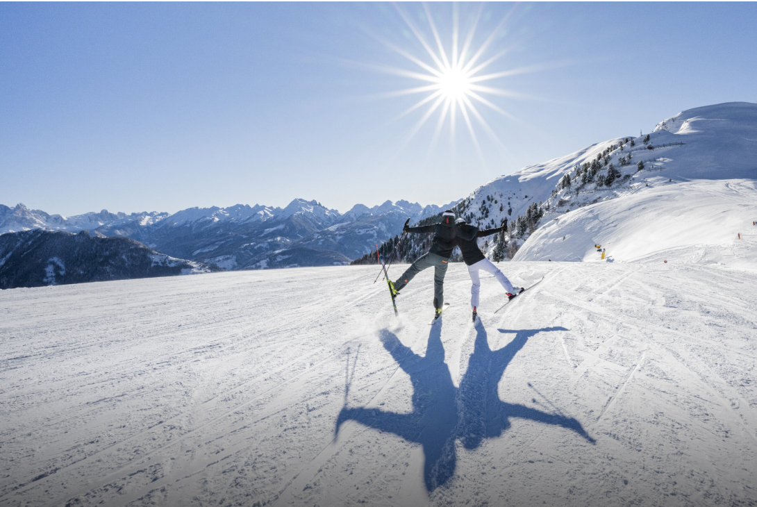 2 Skifahrende posieren glücklich bei bestem Wetter in den Bergen
